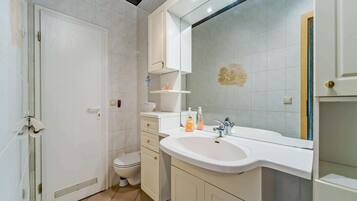 Ein Badezimmer mit weißem Waschbecken, Spiegel und Toilette.