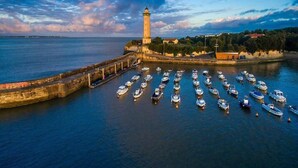 Paisaje costero con un faro y un puerto deportivo lleno de barcos.