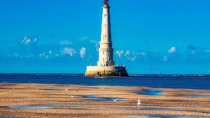 Un faro en una costa rocosa con cielos despejados.