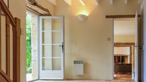 Un pasillo con piso de baldosas, una puerta de madera y una lámpara fijada a la pared.