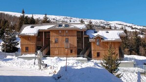 A wooden chalet with a snow-covered roof, a staircase leading to the entrance, and a clear view of the surrounding snowy landscape. - Chalet in France near Ski Slopes (Le Dévoluy)