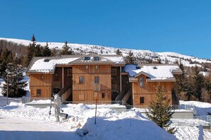 A wooden chalet with a snow-covered roof, a staircase leading to the entrance, and a clear view of the surrounding snowy landscape. - Chalet in France near Ski Slopes (Le Dévoluy)