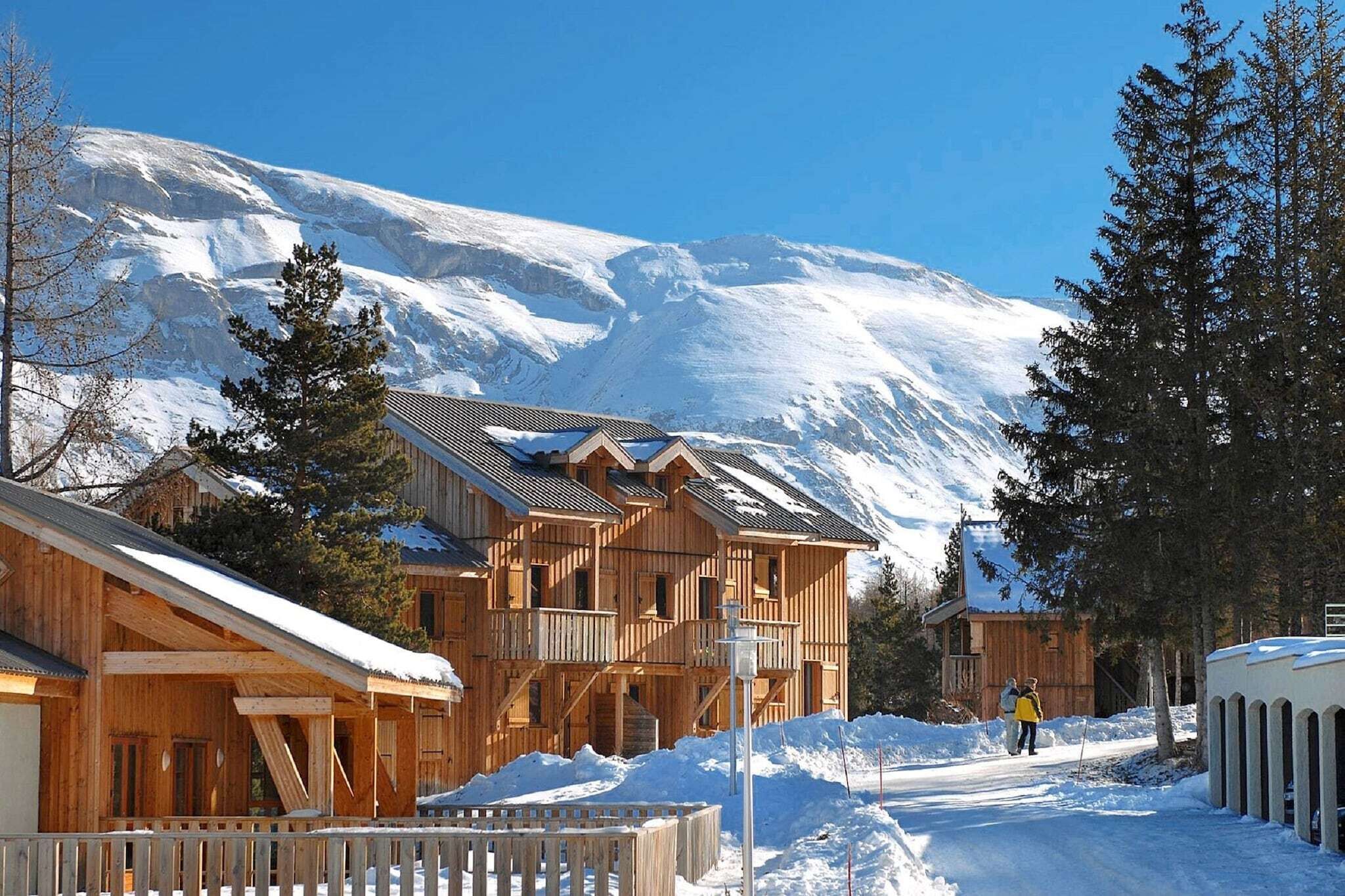 Een houten chalet met meerdere balkons, omgeven door besneeuwde bergen.