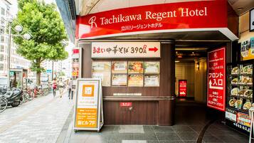 The exterior of the Tachikawa Regent Hotel with a signboard displaying room rates and amenities.