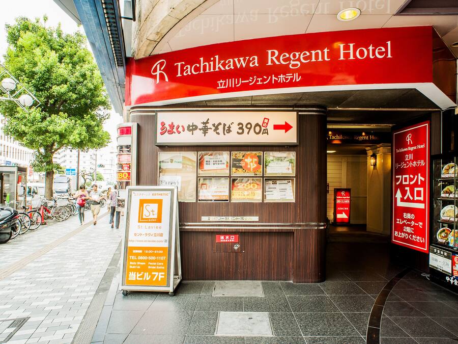 The exterior of the Tachikawa Regent Hotel with a signboard displaying room rates and amenities.