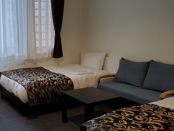 A hotel room with a bed, a sofa, and a small table. - Tachikawa Regent Hotel (Tachikawa)