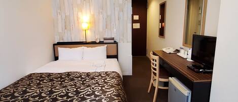 A hotel room with a bed, desk, chair, and a television.