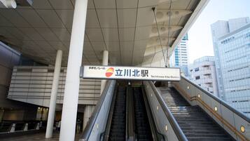 An indoor escalator at a station with a sign reading "Tachikawa-Kita Station".
