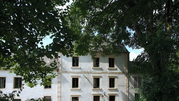 Un edificio a due piani con facciata simmetrica, diverse finestre e un vialetto in ghiaia.