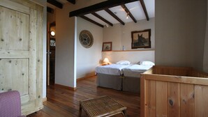 Una stanza con un letto, un tavolino e una panca di legno.