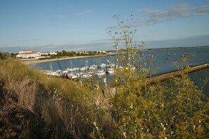 A coastal marina with boats docked, a building with a red roof, and a grassy foreground. - Apartment in France with Ocean Views (Fouras)