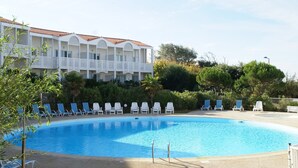 A swimming pool with lounge chairs and a building with balconies. - Apartment in France with Ocean Views (Fouras)