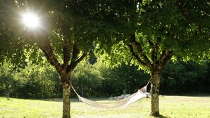 A hammock between two trees in a grassy area with sunlight filtering through the leaves. - Lovely Villa in La Coquille with Swimming Pool (La Coquille)