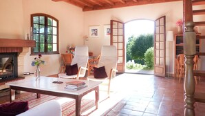 A spacious living room with a fireplace, comfortable seating, and a view of the outdoors. - Lovely Villa in La Coquille with Swimming Pool (La Coquille)