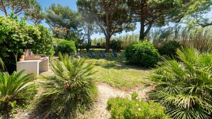 Un jardín con zona de estar, árboles y una estructura de concreto.