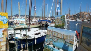 Un puerto deportivo con varias embarcaciones amarradas, rodeado de edificios y obras de arte.