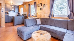 A cozy cabin interior with a modern kitchen, a gray sectional sofa, and a wooden coffee table.