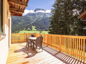 A wooden deck with a table and chairs overlooking a mountainous landscape. - Chalet in Annaberg-Lungotz with shared sauna (Annaberg-Lungötz)