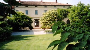 A large, two-story building with a symmetrical facade, a central entrance with a door, and a small staircase leading up to the entrance.