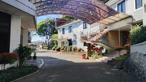 A residential street with a covered walkway, a house with a balcony, and a staircase leading to a second floor. - Hotel Nirwana Batu (Batu)
