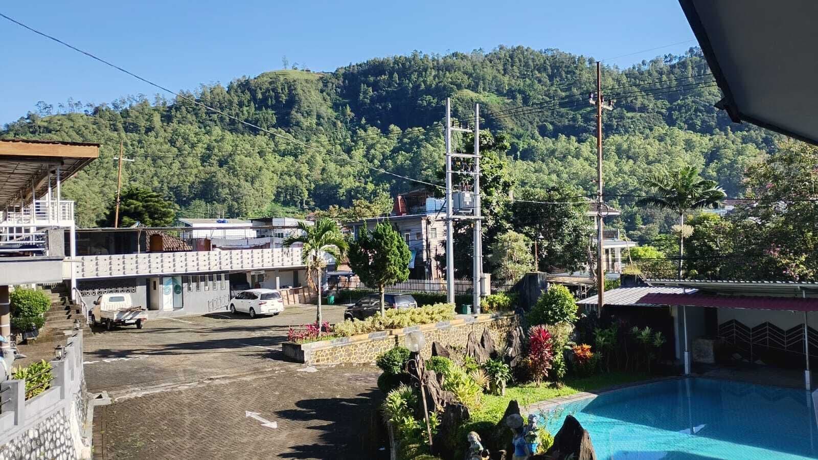 Ein Wohngebiet mit Schwimmbad, Parkplatz und einem Hügel im Hintergrund.