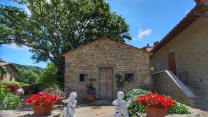 Un bâtiment en pierre avec une porte en bois, des pots de fleurs rouges et des statues en pierre.