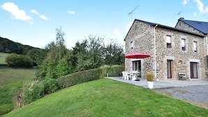 A stone building with a patio, outdoor seating, and a red umbrella. - Peaceful Stay near Lake (Montgothier)