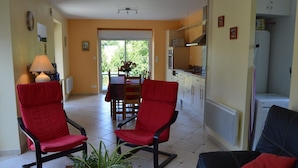 A living room with two red chairs, a black sofa, a dining table with chairs, and a potted plant. - Peaceful Stay near Lake (Montgothier)