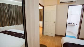A hotel room with a bed, a chair, a door, and an air conditioning unit.