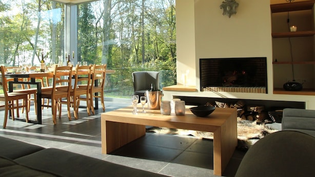 Una sala moderna con comedor, ventanas amplias, chimenea y una zona de estar acogedora.