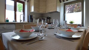 A dining area with a table set for four, equipped with bowls, plates, glasses, and cutlery.