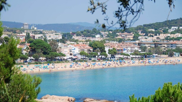A coastal town with a beach, buildings, and rocky outcrops.