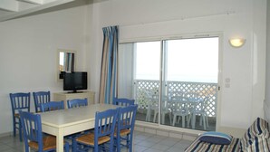 Ein Essbereich mit Tisch und Stühlen, einem Fernseher und einem Balkon mit Blick.