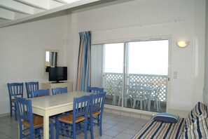 Ein Essbereich mit Tisch und Stühlen, einem Fernseher und einem Balkon mit Blick.