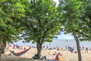 A beach with trees, a hammock, and people relaxing.
