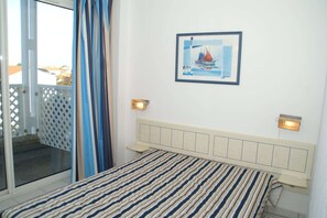 A bedroom with a bed, a view of the outside, and a framed picture on the wall.