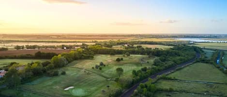 An aerial view of a golf course with a road running alongside it.