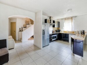 A modern kitchen with a built-in refrigerator, microwave, and oven. There is a staircase leading to an upper level with decorative wall art.