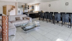 Een moderne woonkamer met een bank, een glazen salontafel en een eethoek met stoelen.