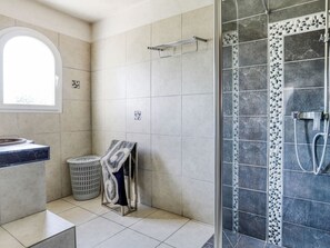 Une salle de bain avec une douche, un lavabo et une fenêtre.