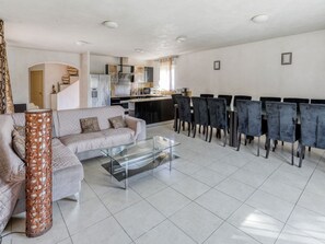 A modern living room with a sofa, a glass coffee table, and a dining area with chairs.