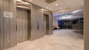 Eine moderne Hotelhalle mit Marmorboden, Holzvertäfelung und einem Aufzug.