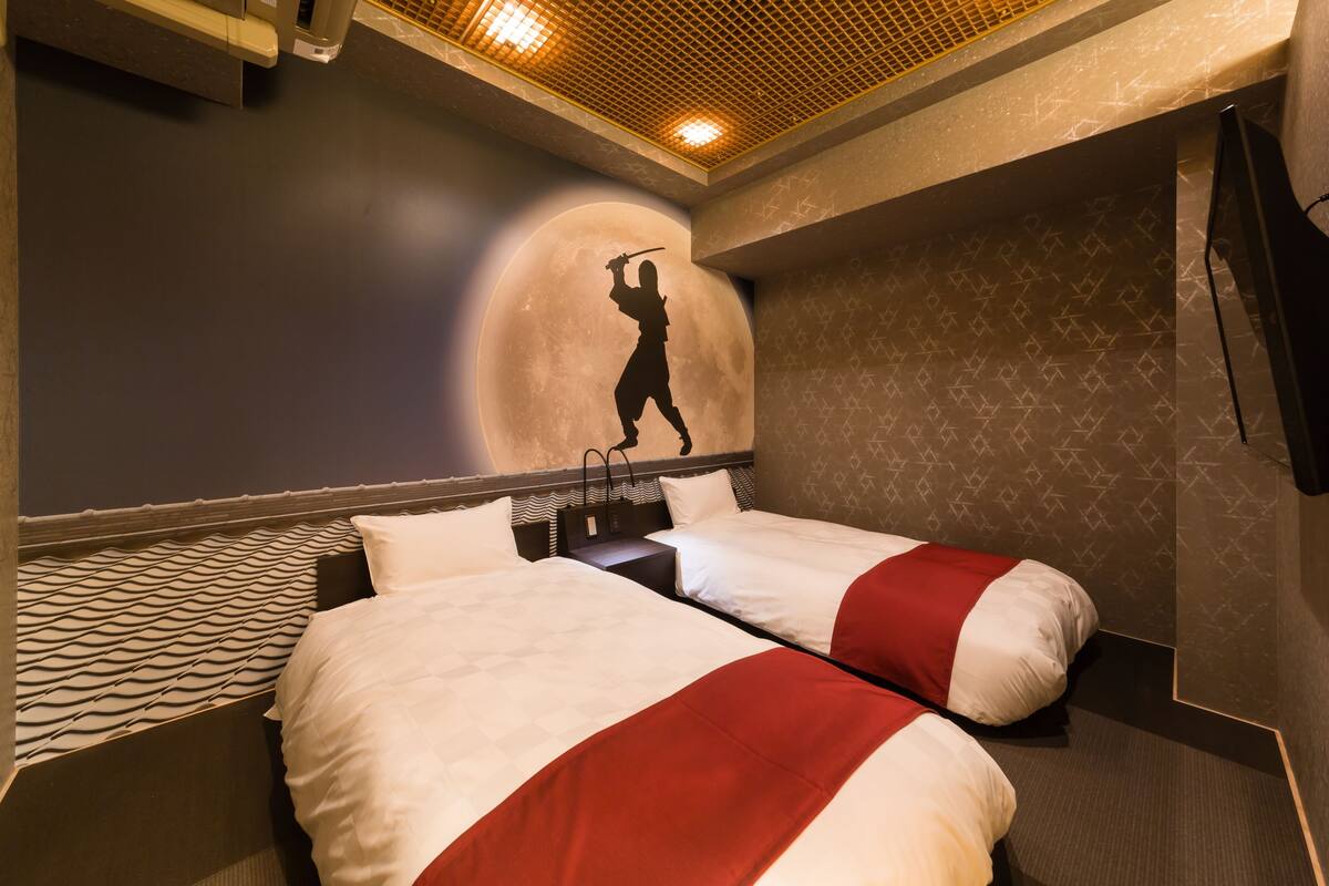 A hotel room with two beds, a wall mural, and a patterned floor.