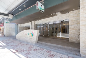 A hotel entrance with a modern design, featuring a stone facade, a glass door entrance, and a signboard with the hotel's name.
