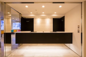 A reception area with a modern design, featuring a reception desk, glass partitions, and a patterned wall.
