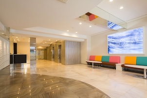 A modern lobby with a reception desk, seating area, and a large digital art display.