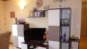 Un soggiorno con una televisione a schermo piatto, una libreria e un vaso decorativo.