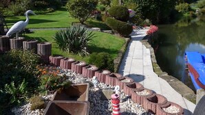 Un giardino tranquillo con uno stagno, un sentiero di legno e un gazebo.