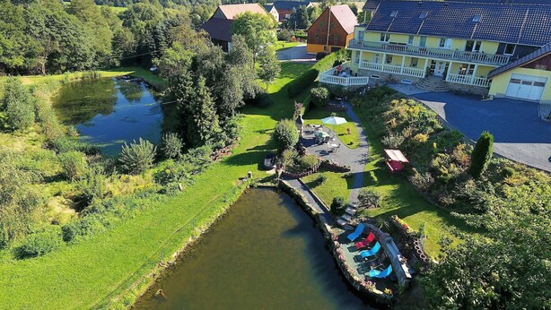 Un hotel sul fiume con area piscina, un giardino e vista sulle colline circostanti.