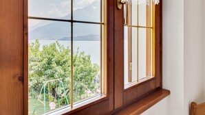 Una ventana con marco de madera y vistas a un lago y montañas.